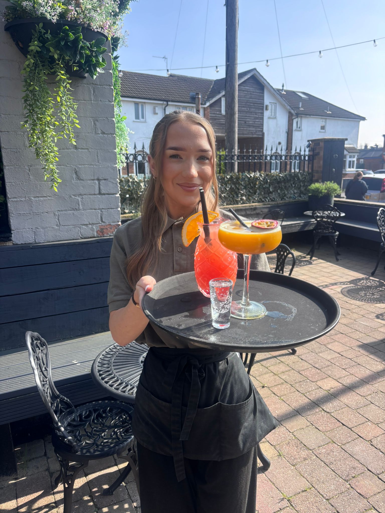 Staff serving cocktails on the sunny terrace at Verona Kitchen & Bar